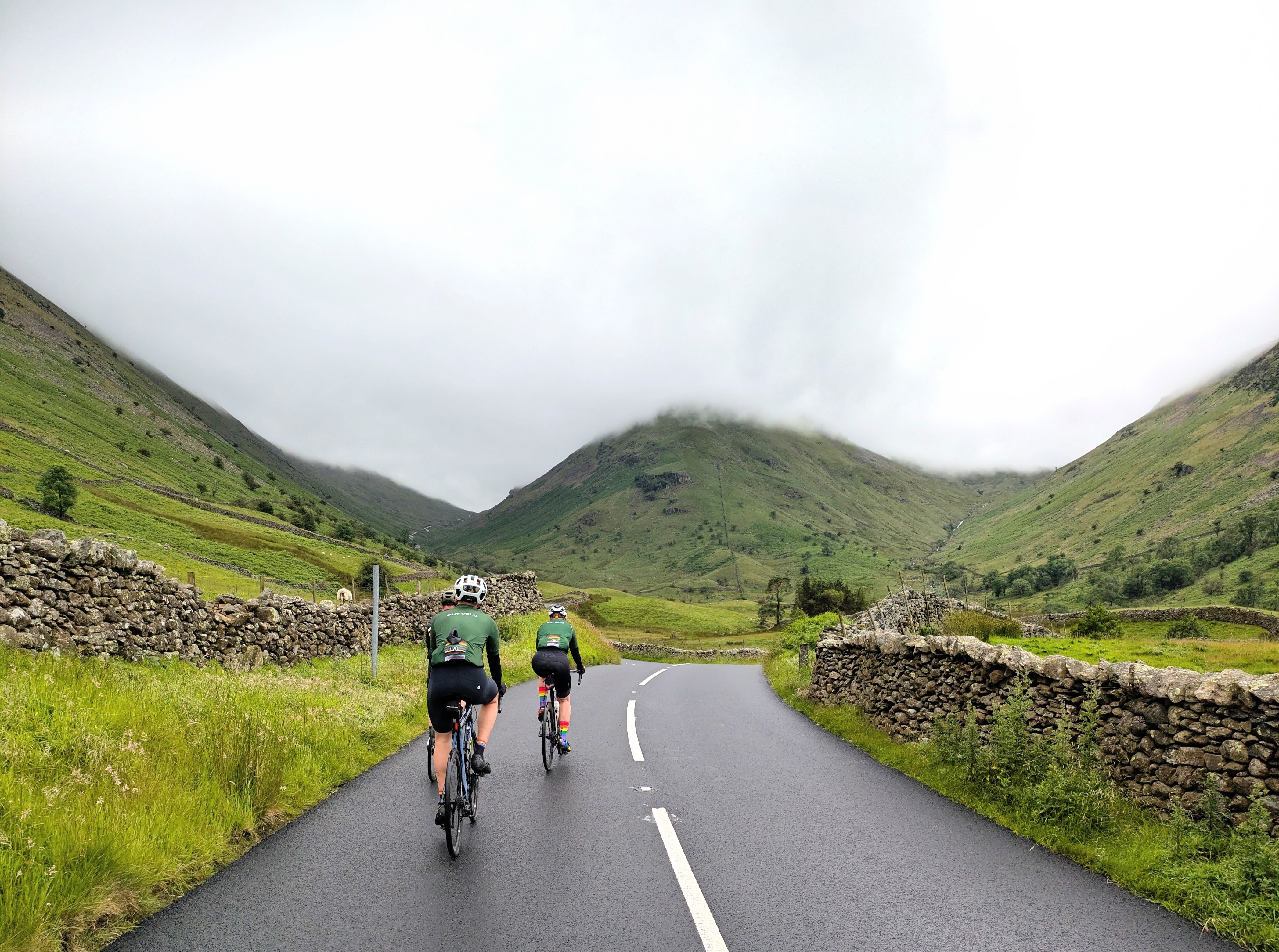 Two Out Velo riders climbing a quiet road through the Kirkstone Pass in the Lake District